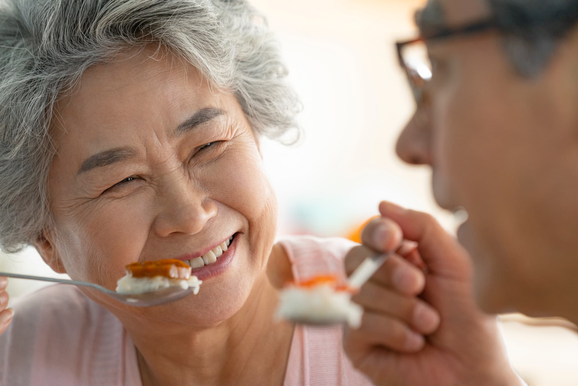 保険適用の入れ歯をして食事を楽しむ高齢女性