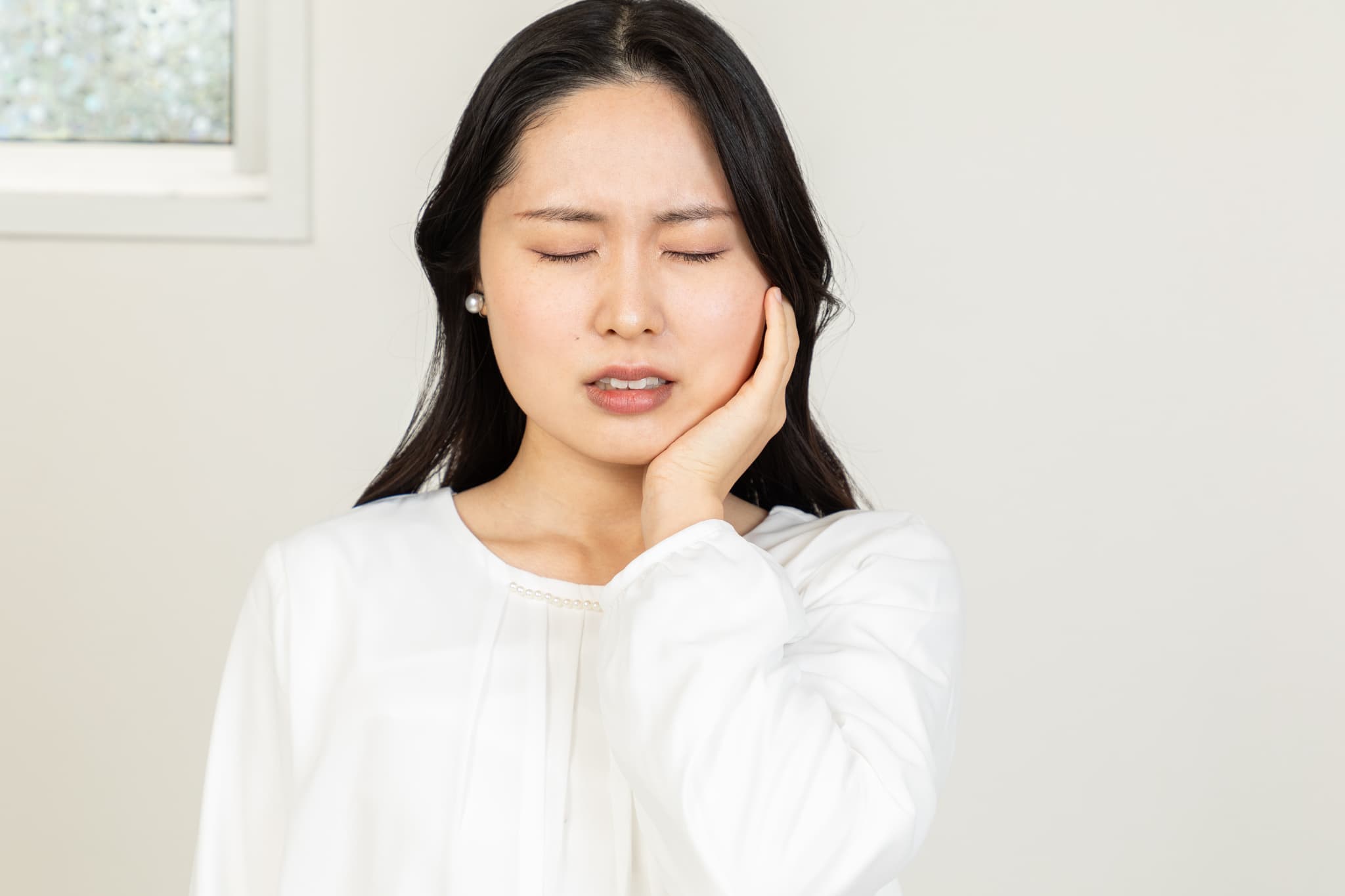 インプラント治療後に痛みが続き頬をおさえる女性