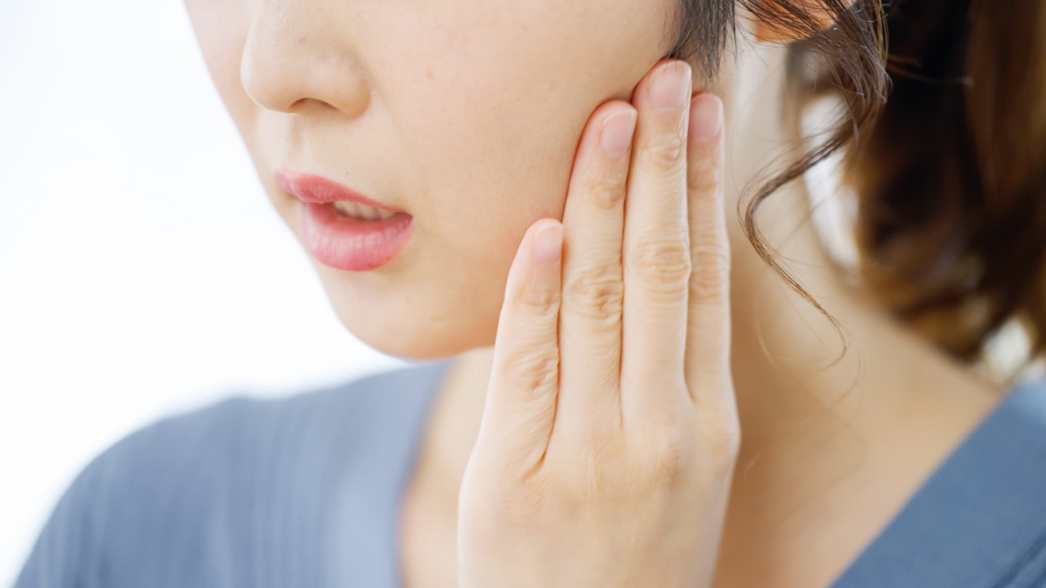 親知らずが痛くて頬を押さえる女性